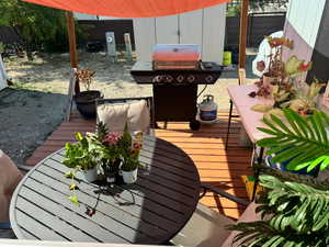 Wooden terrace featuring a grill and fence