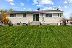 Back of property with entry steps and a lawn