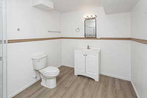 Bathroom with vanity, baseboards, toilet, and wood finished floors