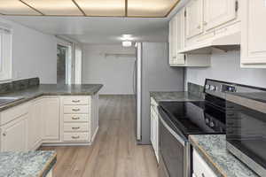 Kitchen featuring under cabinet range hood, light wood-style floors, white cabinetry, and stainless steel range with electric cooktop