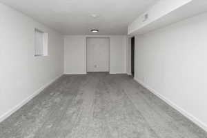 Carpeted spare room featuring visible vents and baseboards