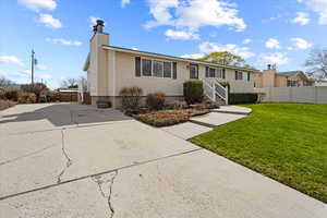 View of front of home featuring a front lawn, fence, and a chimney