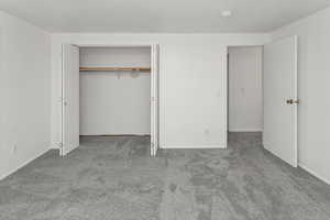 Unfurnished bedroom featuring carpet flooring, a closet, and baseboards