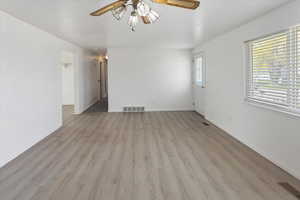 Spare room with visible vents, baseboards, a ceiling fan, and light wood-style floors