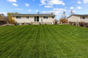 Rear view of property featuring a yard and entry steps