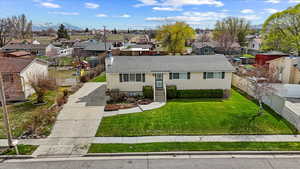 Ranch-style home featuring a mountain view, fence, a front lawn, concrete driveway, and a residential view