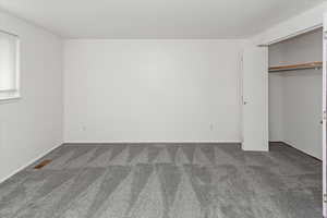 Unfurnished bedroom featuring visible vents, baseboards, a closet, and carpet