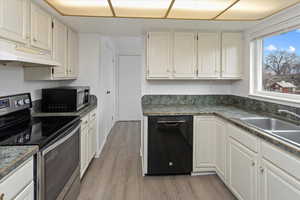 Kitchen with dishwasher, a sink, white cabinetry, and electric stove
