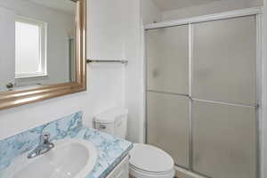 Bathroom featuring toilet, a stall shower, and vanity