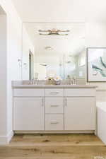 Full bath with wood finished floors, double vanity, and a sink