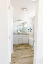 Bathroom with a shower with door, a sink, double vanity, and wood finished floors