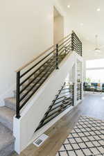 Stairway featuring ceiling fan, visible vents, recessed lighting, wood finished floors, and a high ceiling