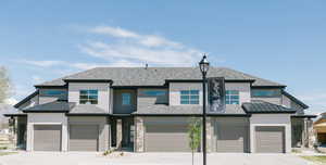 View of front of house with an attached garage, driveway, and roof with shingles