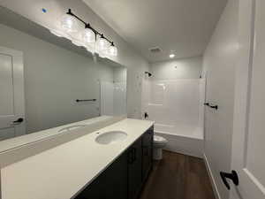 Full bath with vanity, shower / bath combination, toilet, visible vents, and wood finished floors