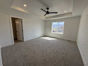 Carpeted empty room with baseboards, recessed lighting, a textured ceiling, a tray ceiling, and ceiling fan