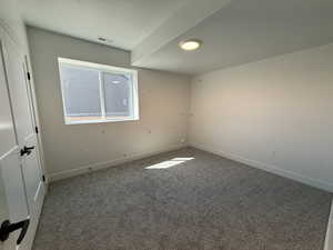 Spare room featuring a textured ceiling, carpet flooring, and baseboards