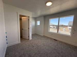 Unfurnished bedroom with a textured ceiling, carpet flooring, baseboards, and visible vents