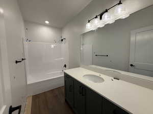 Bathroom with recessed lighting, vanity, wood finished floors, and  shower combination