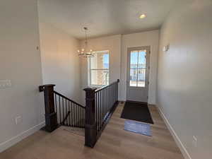 Entryway with wood finished floors, baseboards, a chandelier, and recessed lighting