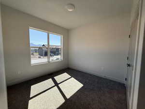 Unfurnished room with dark carpet and baseboards