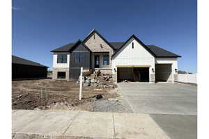 View of front of home featuring brick siding, driveway, board and batten siding, and an attached garage