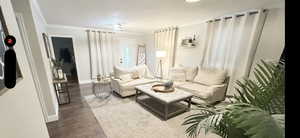 Living area featuring baseboards, crown molding, and wood finished floors