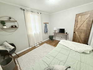 Bedroom featuring crown molding, visible vents, baseboards, and wood finished floors