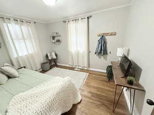 Bedroom featuring visible vents, baseboards, ornamental molding, and wood finished floors