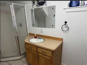 Full bath with a shower stall, vanity, and tile patterned flooring