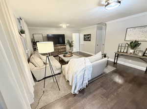 Living room with wood finished floors, baseboards, and ornamental molding