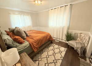 Bedroom featuring visible vents, ornamental molding, wood finished floors, and a textured ceiling