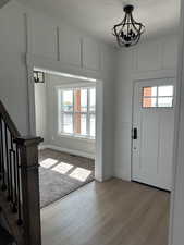 Foyer with wood finished floors, a notable chandelier, stairs, and a wealth of natural light