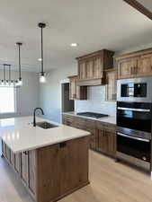 Kitchen with a sink, gas cooktop, light wood finished floors, and stainless steel double oven