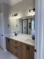 Bathroom with a shower stall, tile patterned floors, double vanity, and a sink