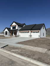 Modern farmhouse featuring driveway, a garage, and stone siding