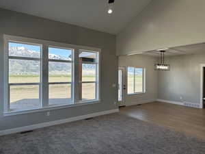 Carpeted empty room featuring high vaulted ceiling, baseboards, and visible vents