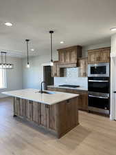 Kitchen featuring a sink, light wood-style flooring, appliances with stainless steel finishes, and decorative backsplash