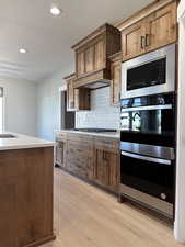 Kitchen featuring light wood-style floors, light countertops, backsplash, and a textured ceiling
