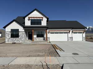 Modern farmhouse style home featuring driveway, board and batten siding, stone siding, and an attached garage