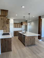 Kitchen featuring tasteful backsplash, light wood-style flooring, gas cooktop, dishwasher, and a sink