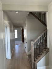 Corridor featuring baseboards, recessed lighting, wood finished floors, and stairs