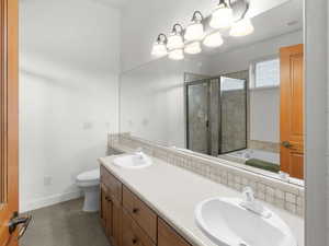 Bathroom with a sink, toilet, a stall shower, jetted tub, and baseboards
