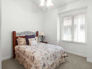 Carpeted bedroom with baseboards, a ceiling fan, and lofted ceiling