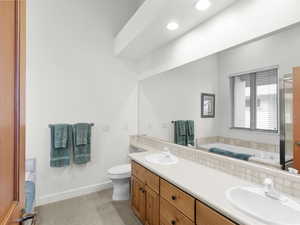 Bathroom featuring double vanity, a stall shower, jetted tub, baseboards, and a sink
