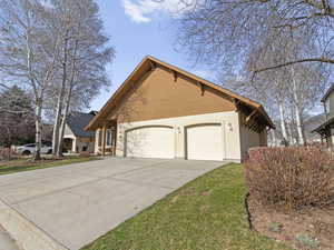 View of side of home featuring driveway, stucco siding, and an attached garage