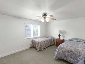 Carpeted bedroom with baseboards and a ceiling fan