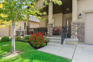 Property entrance with covered porch, stone siding, and stucco siding