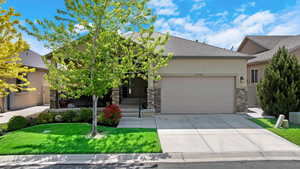 View of front of home featuring stucco siding, concrete driveway, an attached garage, and stone siding