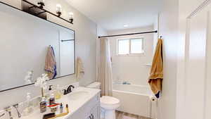 Bathroom featuring shower / tub combo, vanity, toilet, and wood finished floors