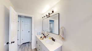 Bathroom with wood finished floors, double vanity, and a sink